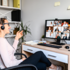 A photo of a happy woman on a video call with 9 other people in a home office.