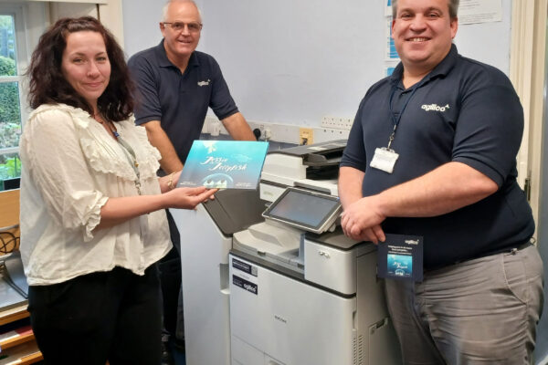 A member of the team at Chailey St Peter's Primary School receiving their new refurbished device and a copy of the Jessie the Jellyfish book.