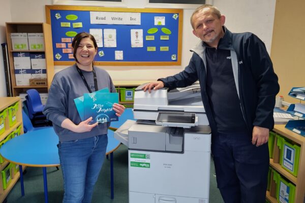 A member of the team at Heart Academies Trust receiving their new refurbished device and a copy of the Jessie the Jellyfish book from Agilico Installations Operative, Serge Rydosz.